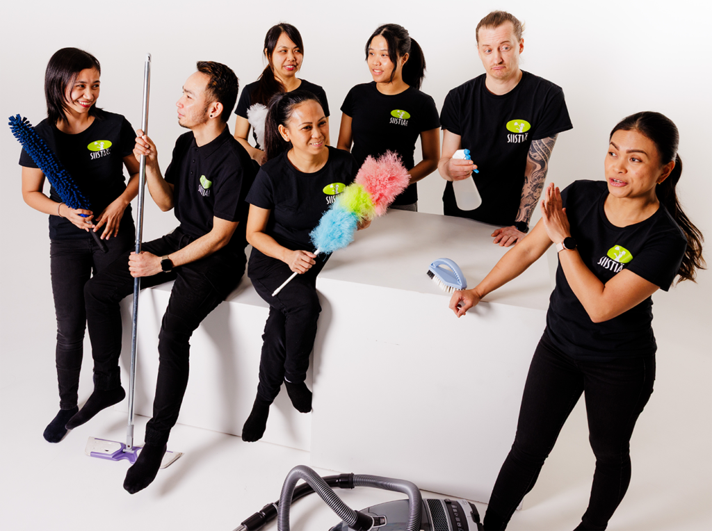 SIISTIÄ! Siivouspalvelut -tiimi poseeraa yhdessä siivousvälineiden kanssa valkoisella taustalla